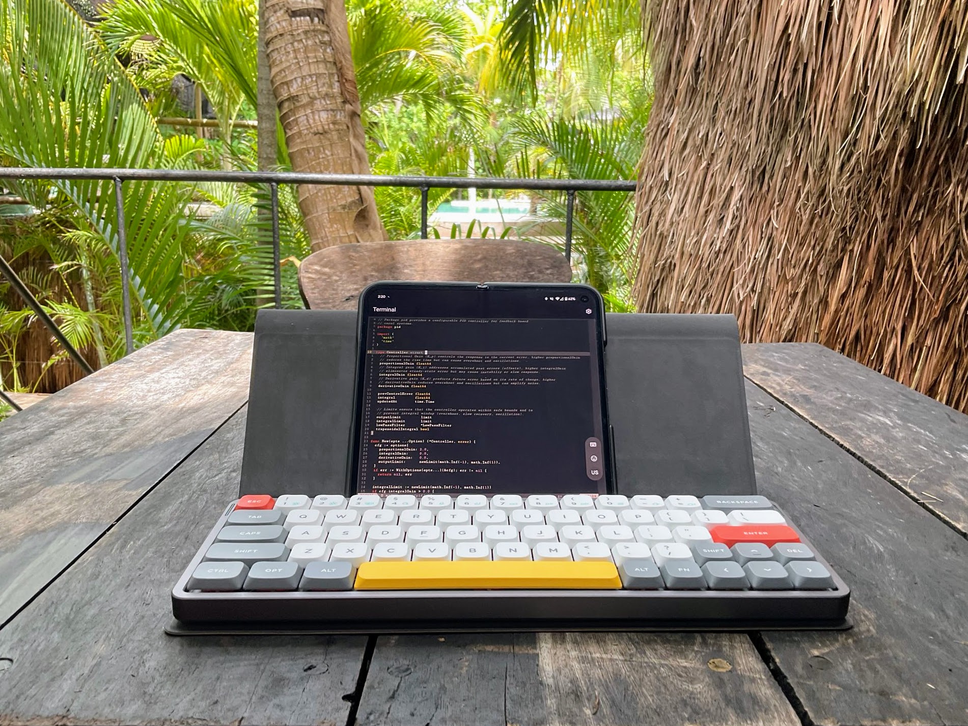 Pixel Fold paired with a NuPhy Air60 V2 keyboard running a terminal session on a rustic outdoor table, surrounded by lush greenery.